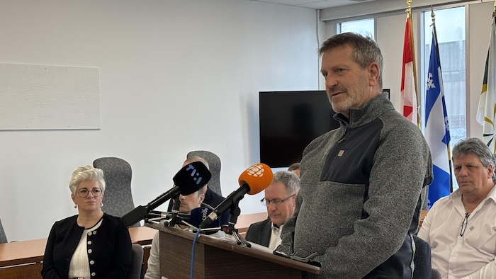 Jeannot Vich, près d'un lutrin, prenant la parole. Derrière lui, des conseillers sont assis.