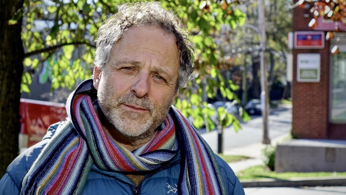 Jeff Karabanow photographié dehors, une grosse écharpe autour du cou.