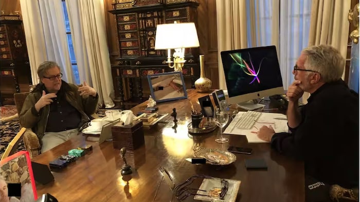 Deux hommes parlent de part et d'autre d'un bureau.