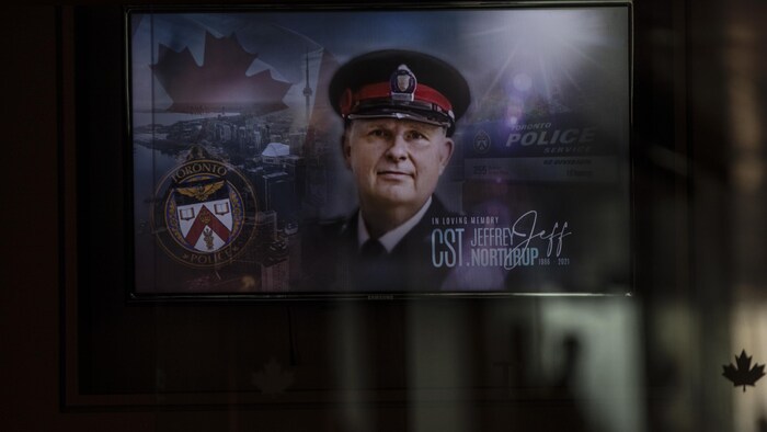 Le visage du policier sur un grand écran.