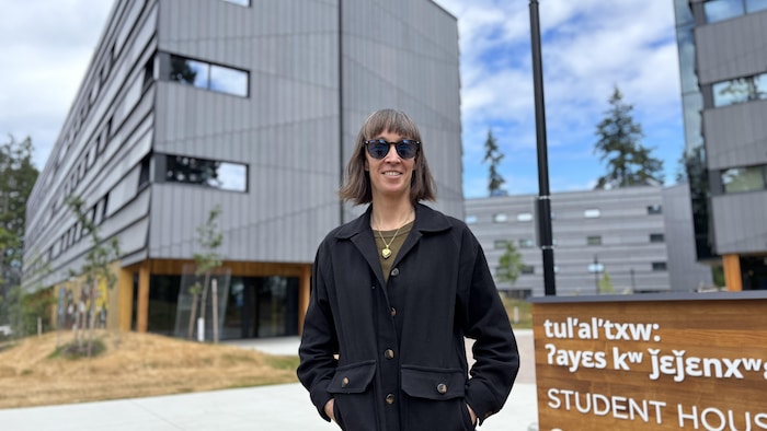 Une femme avec en arrière-plan une résidence universitaire. 