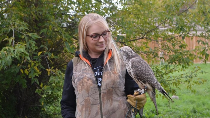 Une femme avec un oiseau posé sur sa main.