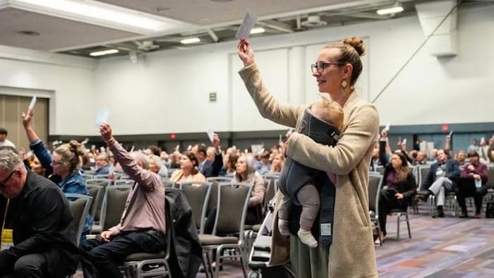 Une femme portant un bébé vote lors d'une séance d'un conseil de district.