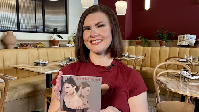 Jennifer Bettencourt qui tient un disque compact de sa compilation.