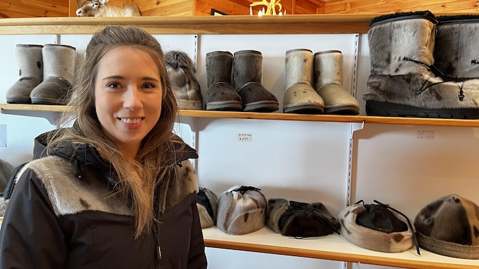 Jennifer Shears, propriétaire d'une boutique de souvenirs et du Musée de faune à Rocky Harbour. Elle pose devant des chapeaux et des bottes en peau de phoque.