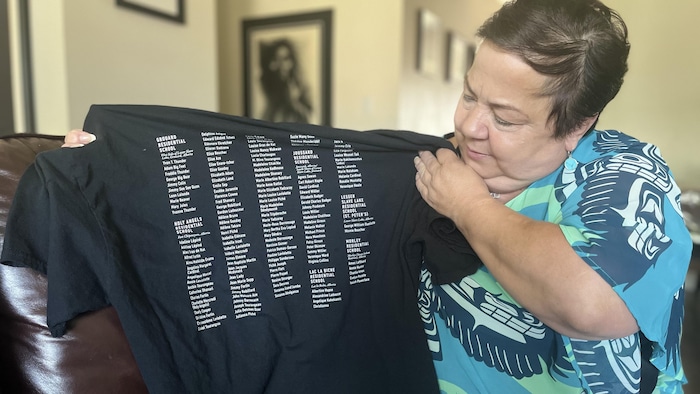 A woman showing a t-shirt with names of children on it.