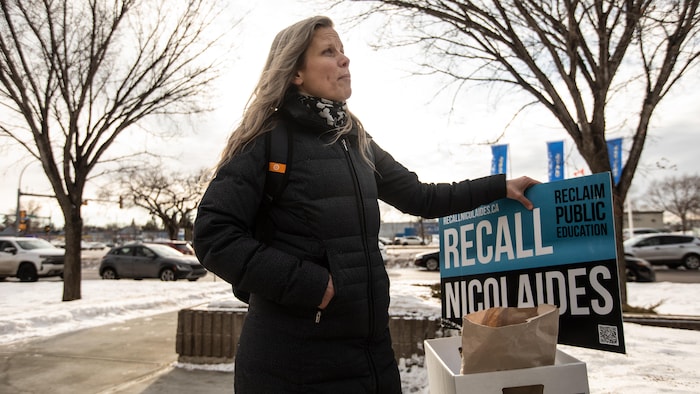 Une personne tient une pancarte sur laquelle on peut lire « Renvoyez Nicolaides ».