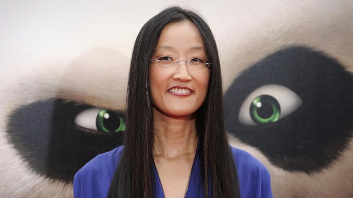 Jennifer Yuh Nelson, souriant devant une affiche géante du film Kung Fu Panda 2.