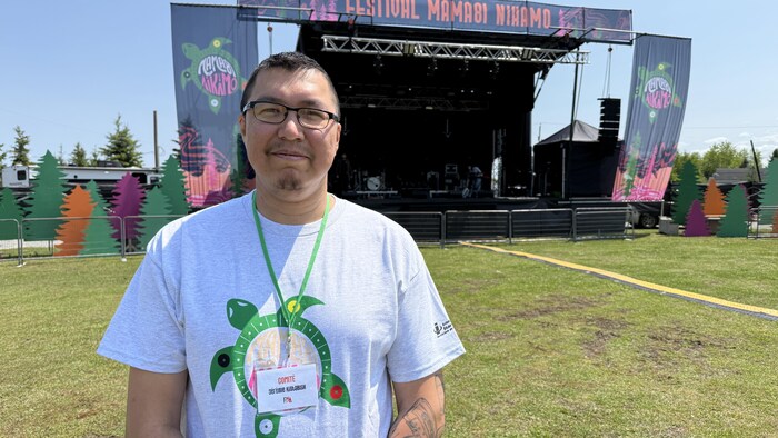 Un homme debout regarde la caméra. 