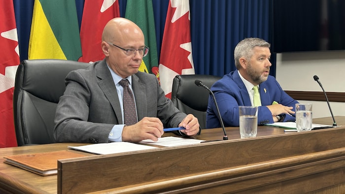 Jeremy Harrison, ministre responsable de la Société d’assurances de la Saskatchewan, et Kent Campbell, PDG de la SGI, en conférence de presse.