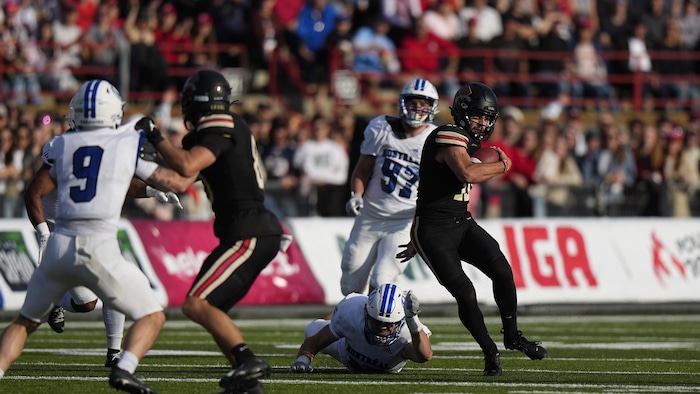 Il tribunal avec le ballon, laissant un joueur des Carabins au sol derrière lui.