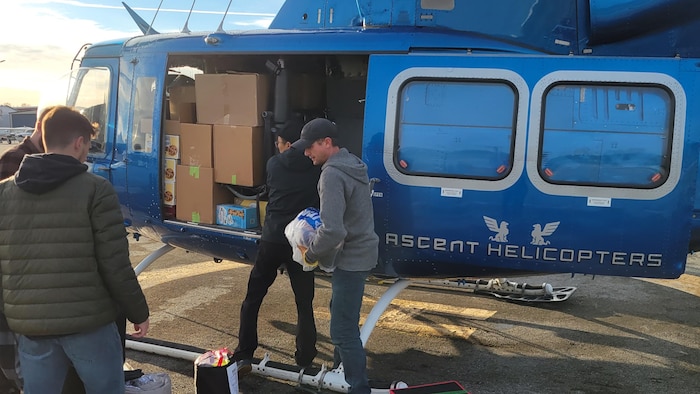 Un groupe de personnes charge des produits de première nécessité dans un hélicoptère.