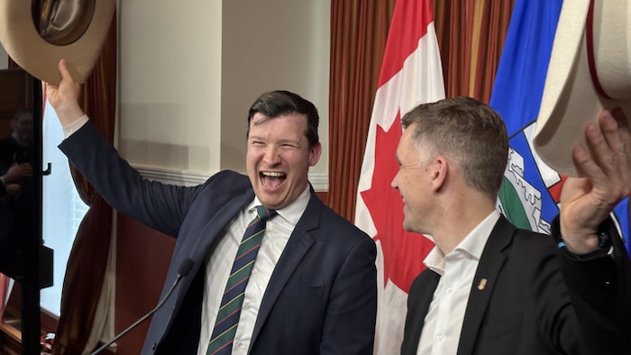 Jeromy Farkas et Bruno Marchand se regardent un chapeau de cowboy à la main.