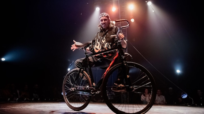Un homme est sur scène avec un vélo.