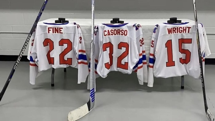 trois jerseys de hockey et trois crosses de hockey sur une table