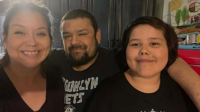 Un homme, une femme et un enfant sourient à la caméra.