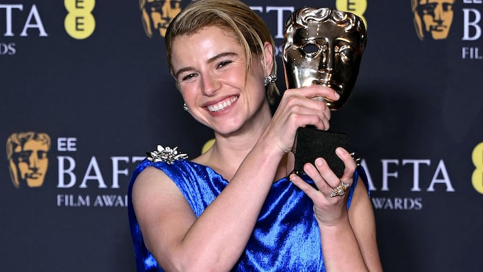 Une femme soulève un trophée. 