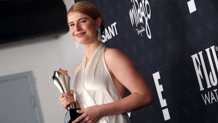 Une femme vêtue de blanc pose avec un trophée.