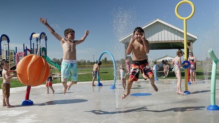 Deux garçons sautent dans un jeu d'eau.