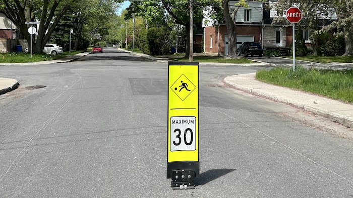 Une rue avec un panneau de limite de vitesse.