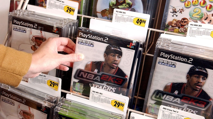 Quelqu'un prend un exemplaire du jeu vidéo « NBA 2K3 » dans un magasin. 