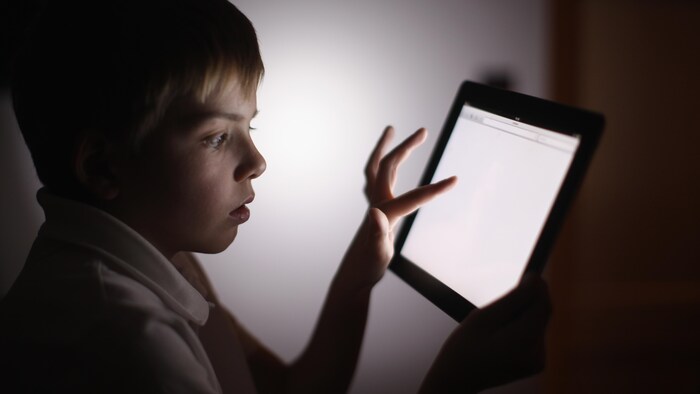 Un jeune garçon utilise une tablette informatique.