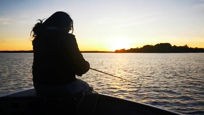 Une jeune Anichinabée de Lac-Simon pêche alors que le soleil se couche.