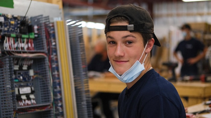 Un jeune homme sourit dans une usine.