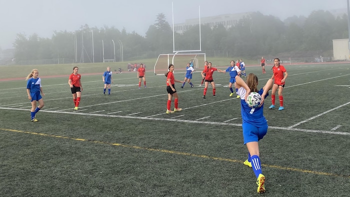 Une joueuse de soccer s'apprête à lancer le ballon pour le remettre en jeu.