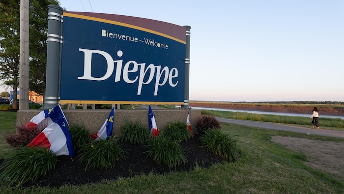 Une enseigne sur laquelle on peut lire Dieppe entourée de drapeaux de l'Acadie.