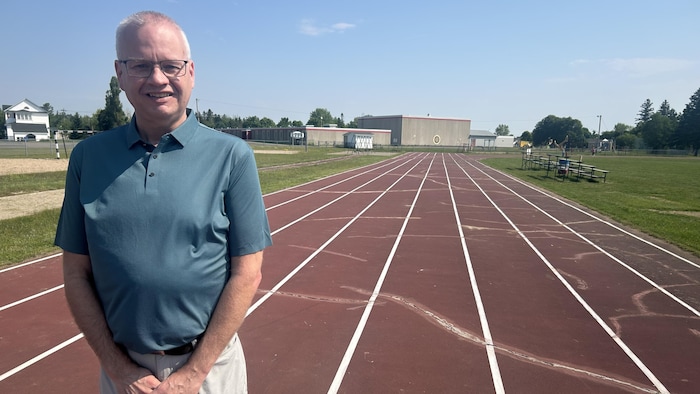 Un homme se tient bien droit au milieu d'une piste d'athlétisme extérieur.