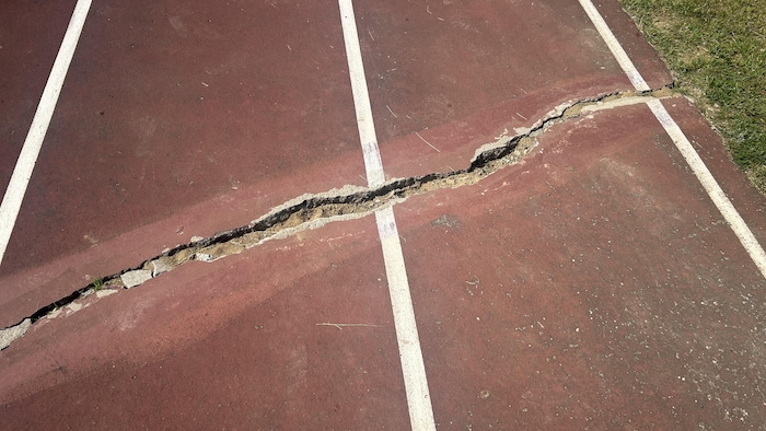 Une fissure est formé sur le sol d'une piste d'athlétisme.