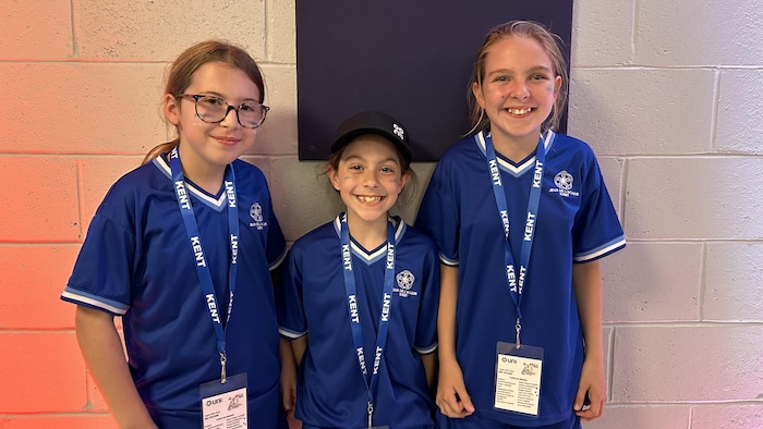 Trois jeunes joueuses de mini-handball posent pour la photo, vêtues des couleurs de la délégation de Kent.