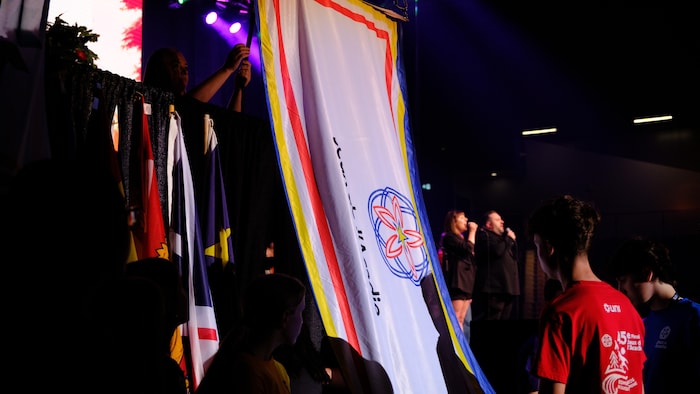 Des jeunes qui accrochent un drapeau.