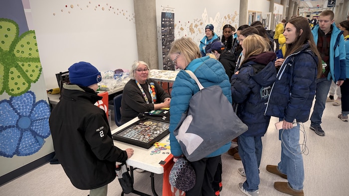 Des gens entourent une table remplie d'épinglettes.
