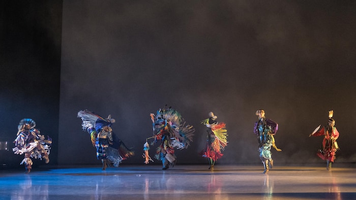 Six jeunes dansent sur scène dans des costumes très colorés et élaborés.