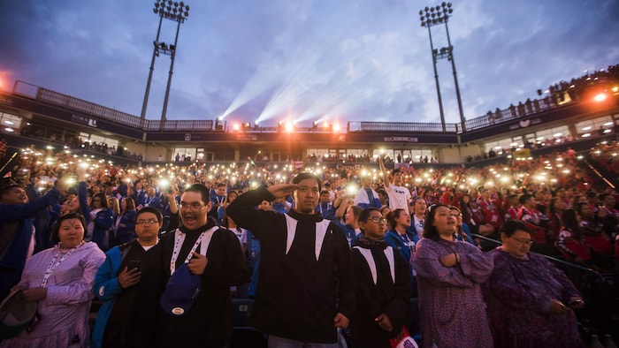 Des participants à la cérémonie d'ouverture des Jeux autochtones saluent et chantent l'«Ô Canada».