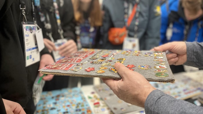Une personne tend un panneau rempli d'épinglettes à l'une des tables d'échange installées durant
les Jeux d'hiver de l'Arctique 2023.