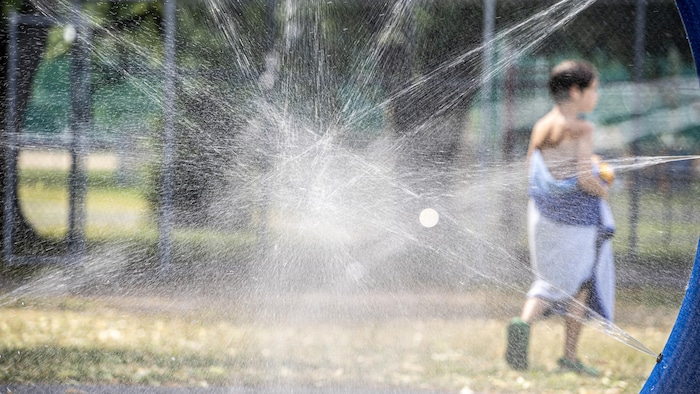 Un enfant de dos dans un parc de jeux d'eau.