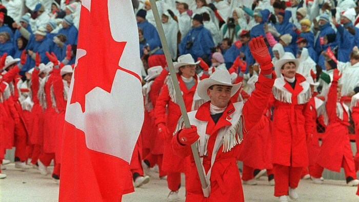 Le patineur Brian Orser porte le drapeau canadien à la cérémonie d'ouverture des JO, suivi de la délégation d'athlètes canadiens.