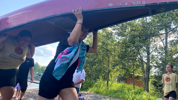 Deux filles portent un canot sur la tête.