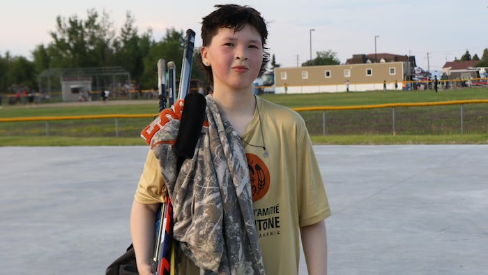 Eli Boivin porte ses bâtons de hockey.
