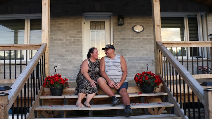 Le couple pose devant chez lui.