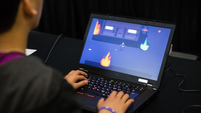 Un jeune joue à un jeu vidéo sur un ordinateur. 