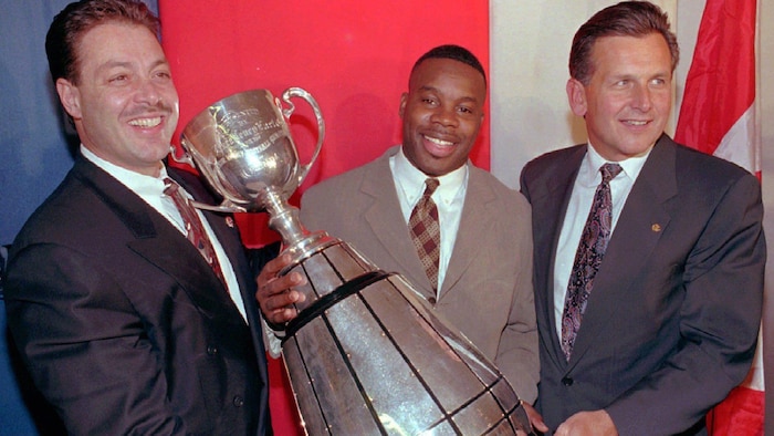 Jim Speros, Tracy Ham et Larry Smith brandissent la coupe Grey.