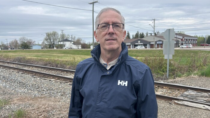 Un homme debout devant des rails