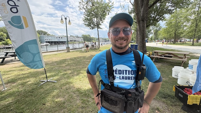 Un homme souriant à la caméra qui pose à l'extérieur.