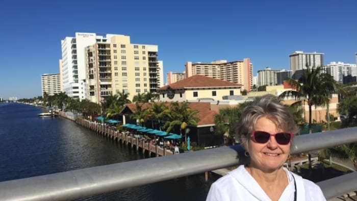 Jo-Ann Rowe pose, souriante, sur un pont surplombant un canal, devant des édifices.