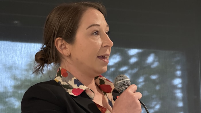 Joanie Bolduc parle au micro en s'adressant au public.