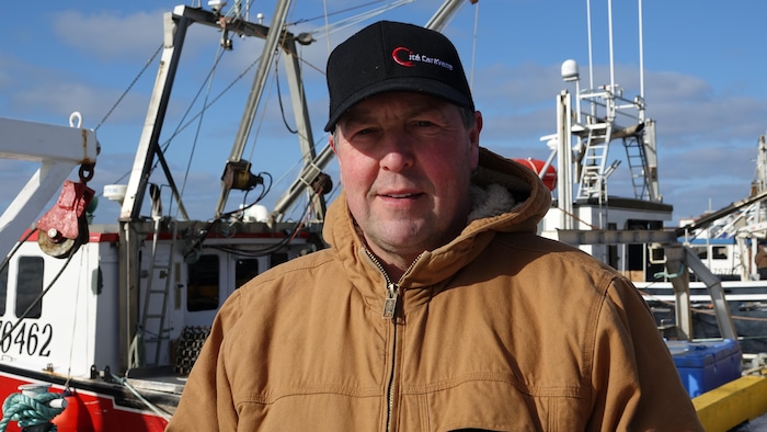 Jocelyn Thériault devant des bateaux de pêche.